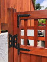 Hand-forged rustic hammered brackets and braces on a wooden gate, showcasing durable and decorative hardware.
