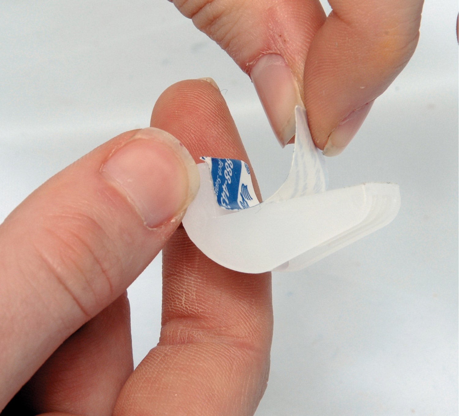 Clear drawer bumpers being peeled from a backing, ideal for protecting surfaces and reducing noise. 10 pack.