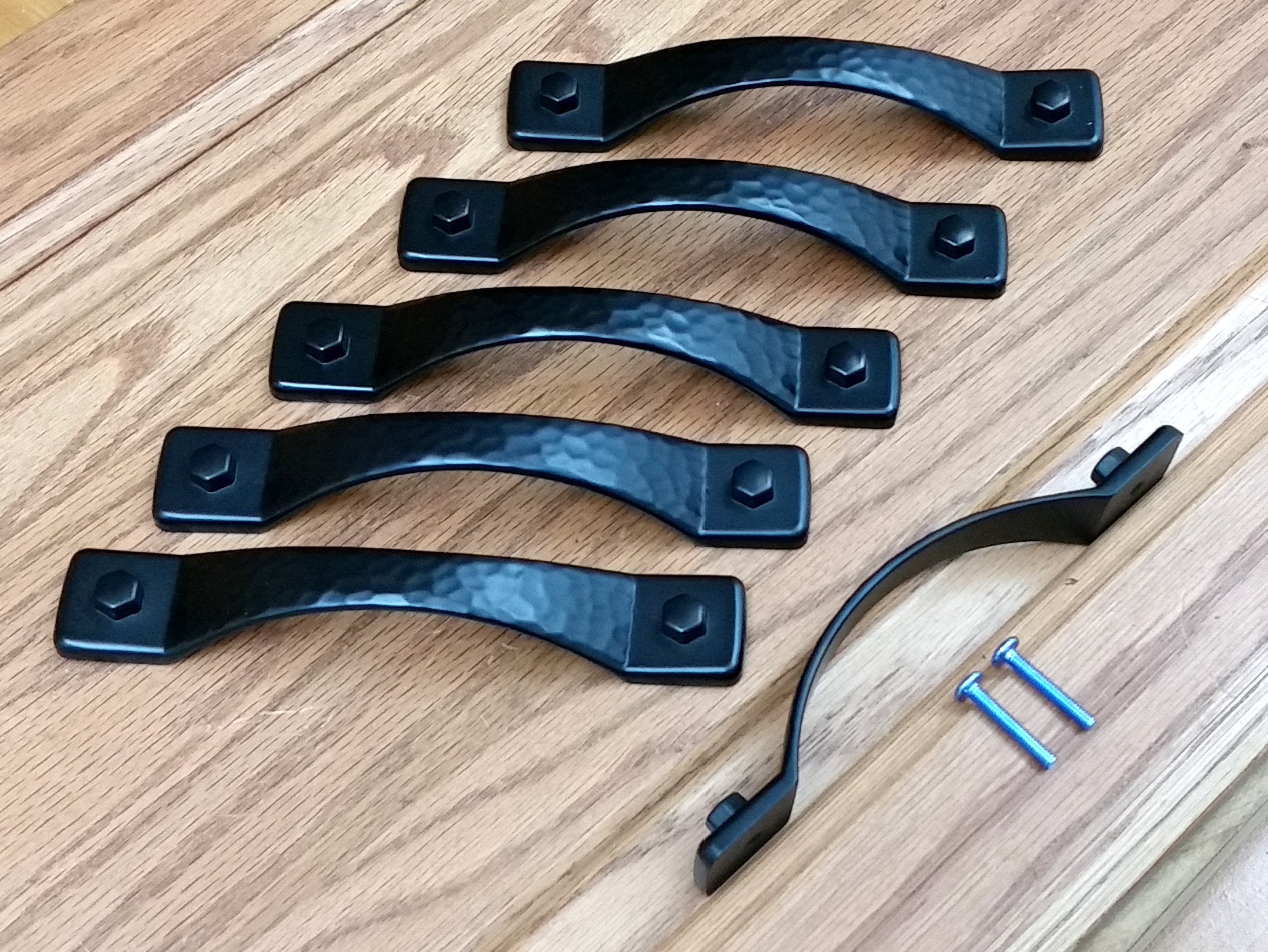 Rustic hammered drawer pulls in matte black finish, featuring a sleek design with accompanying screws for installation.