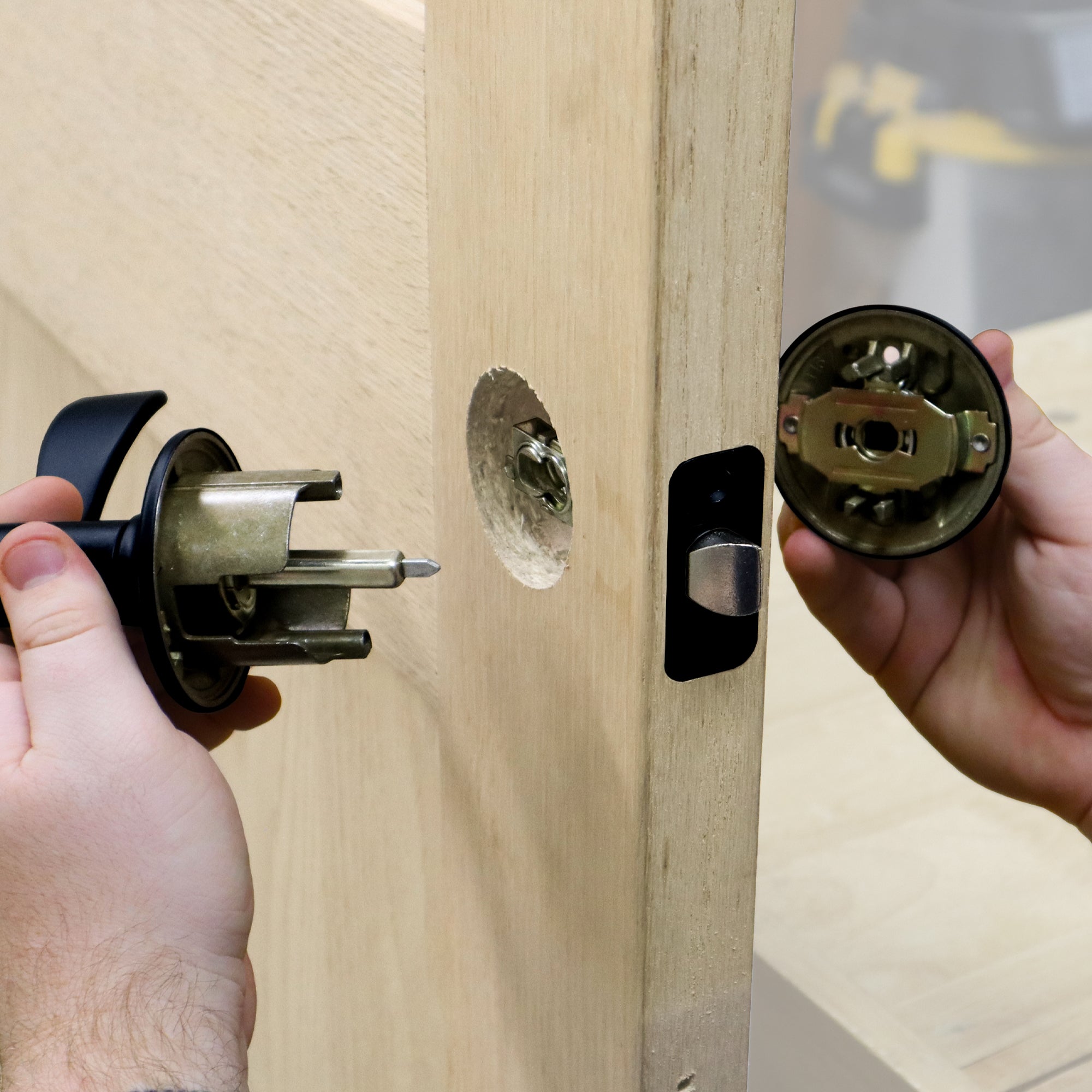 Self-clamping installation jig for locks and knobs, demonstrating use on a wooden door with tools in hand.