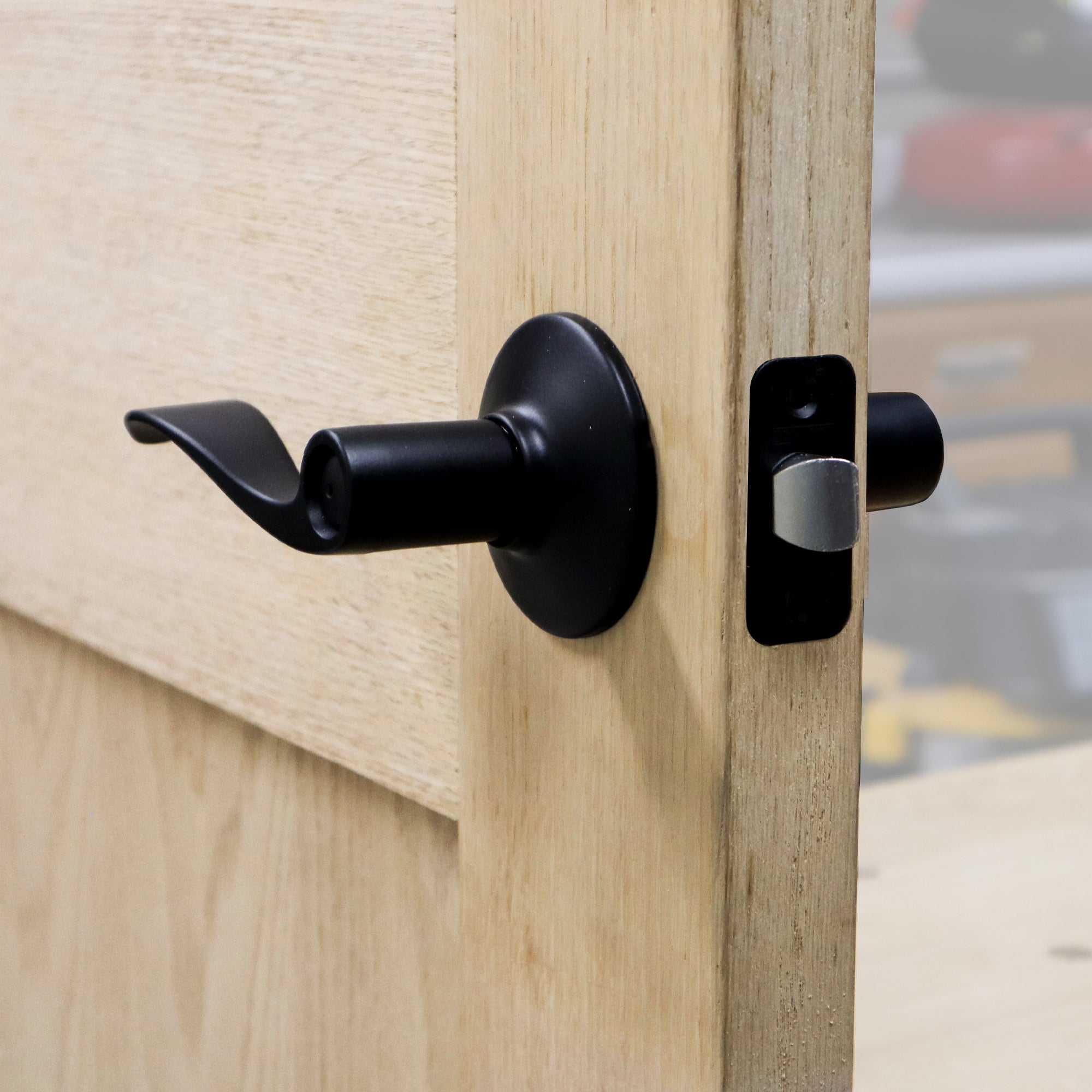 Self-clamping installation jig for locks and knobs, designed for professional use, shown on a wooden door.