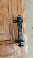 Mini 4-inch bridge door pull in black finish, mounted on a wooden door for easy access and stylish design.