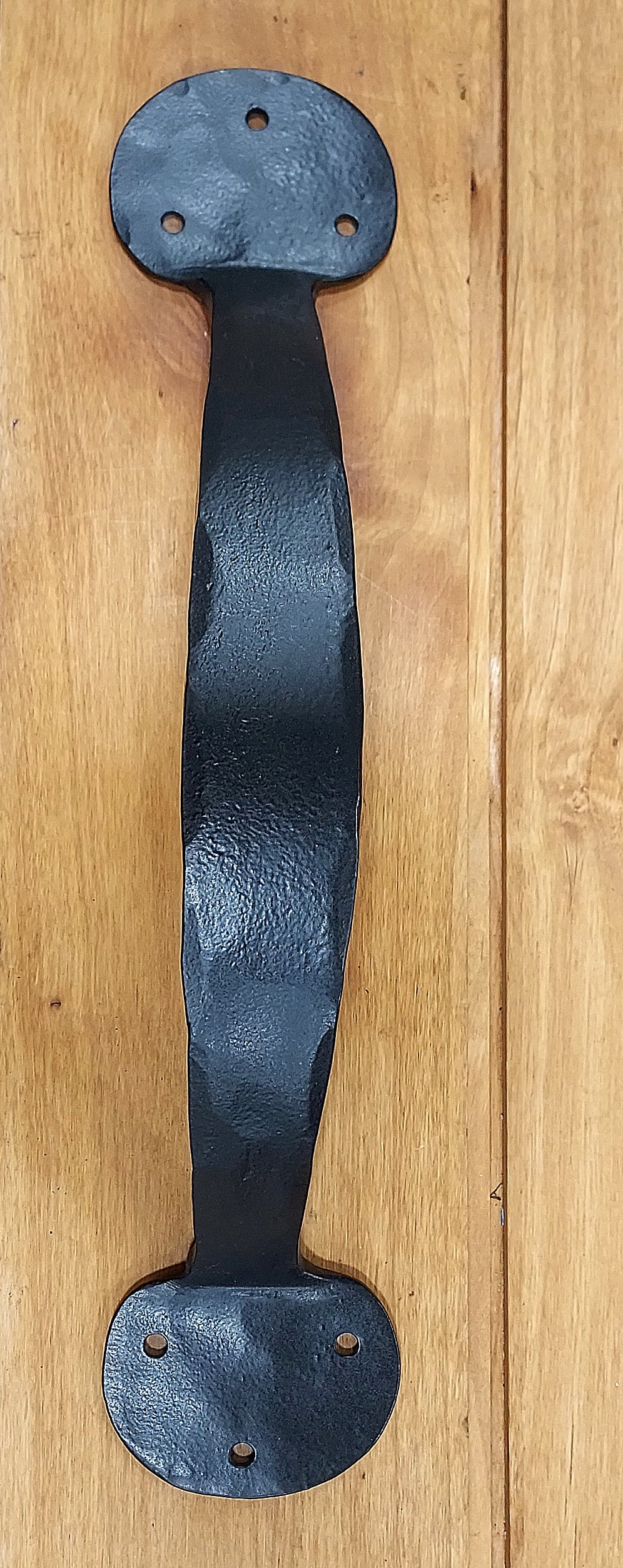 Bean style door handle in black finish, featuring a textured design and rustic head screws, available in various sizes.