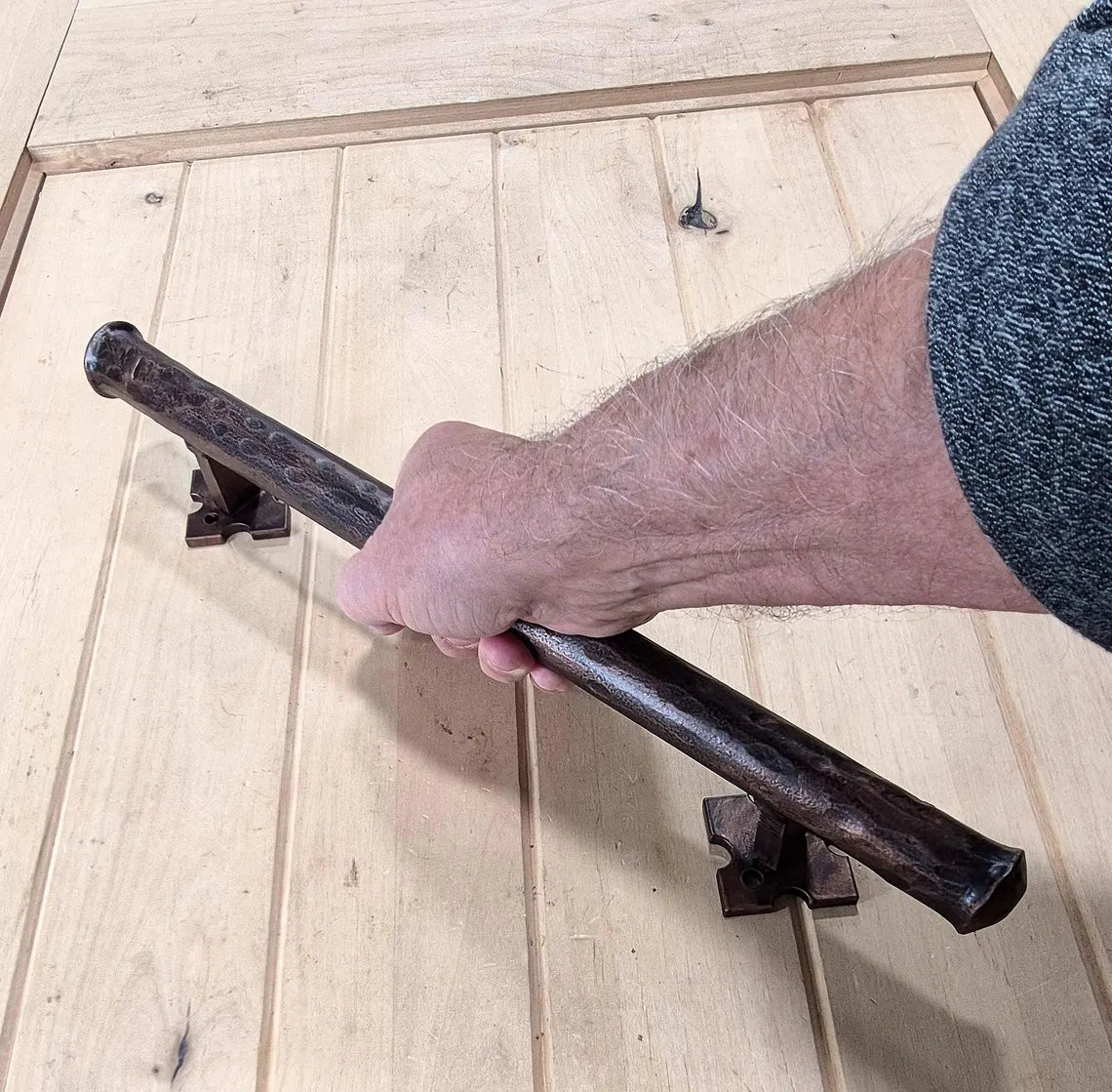 Round bar distressed barn door handle, 1-inch diameter, shown in use on wooden door, available in various sizes and finishes.