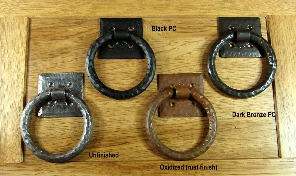 Distressed ring pull with a 4-inch diameter and hammered back plate in various finishes displayed on wood.