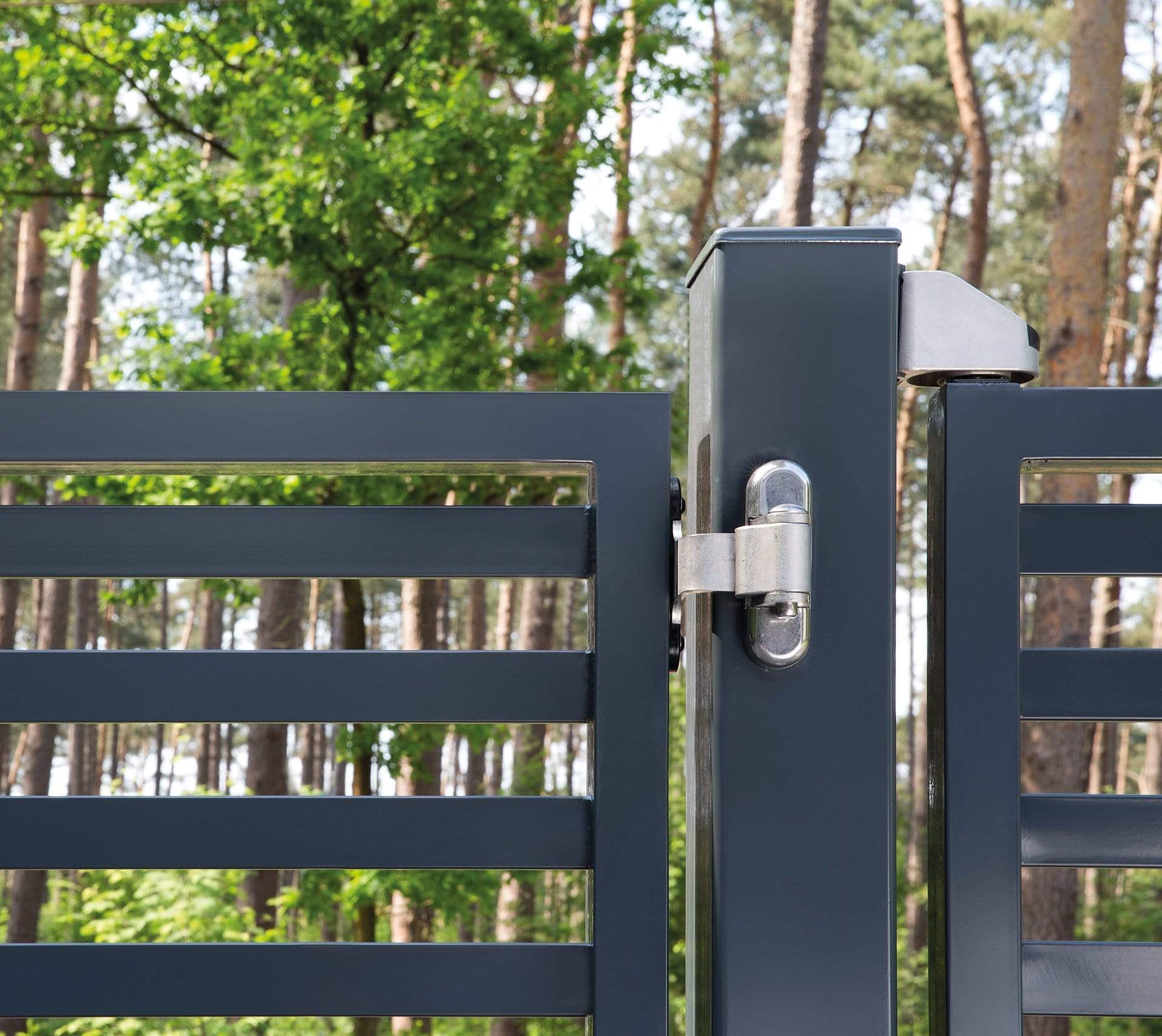 Stainless steel 90° 2-way adjustable bearing gate hinges installed on a modern gate in a wooded area.