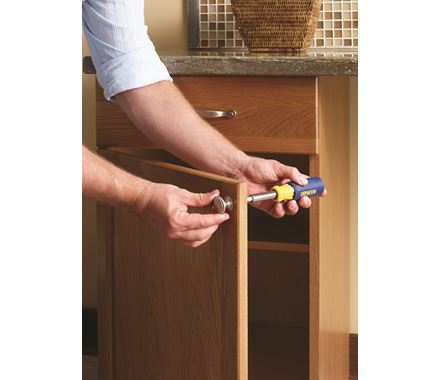 Cabinet door mounting template for knobs and pulls, adjustable from 3 inches to 128mm, shown in use with a screwdriver.