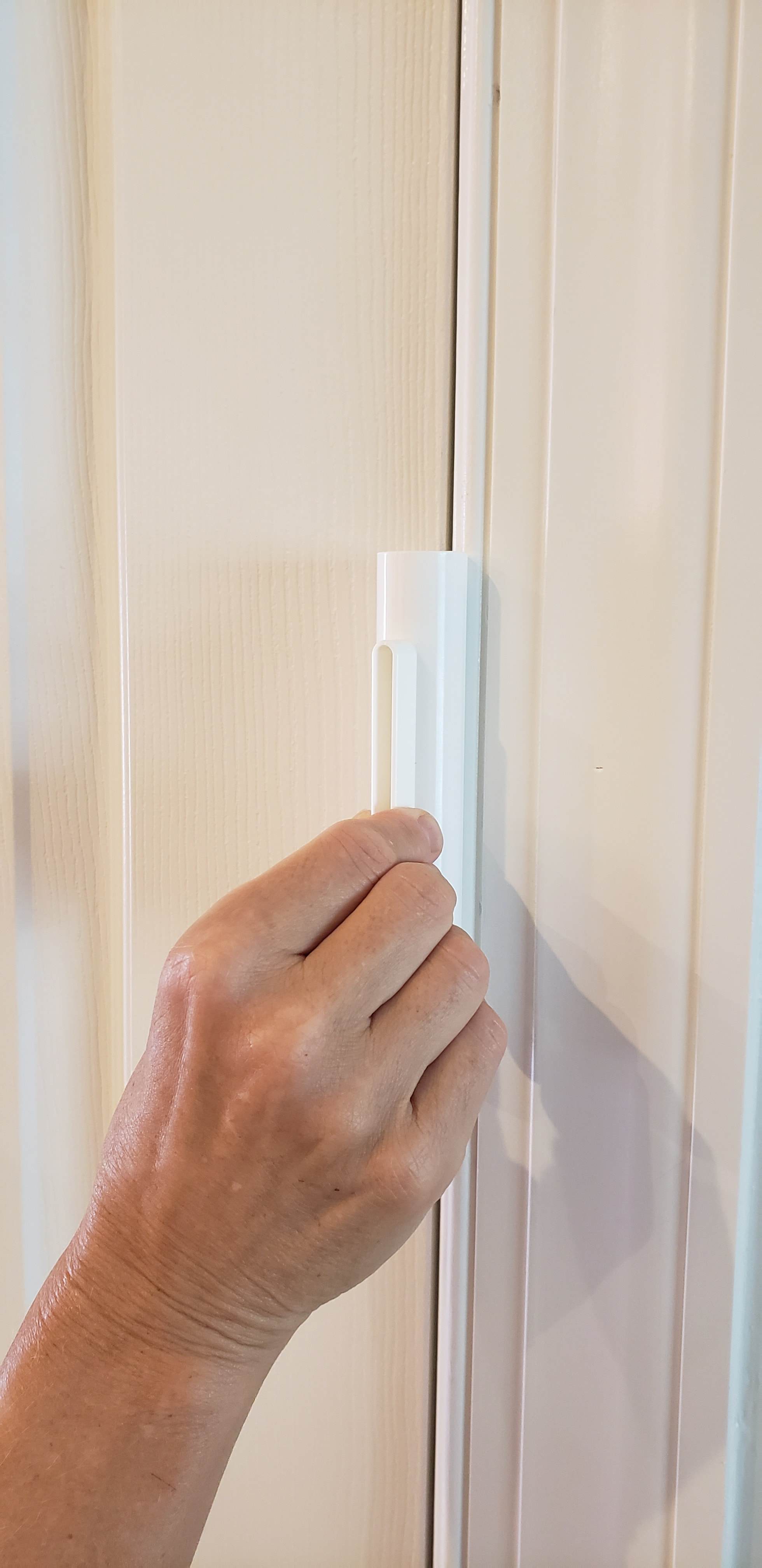 Hand using the Hinge Hero door hinge lubrication tool on a door, demonstrating its application for smooth operation.