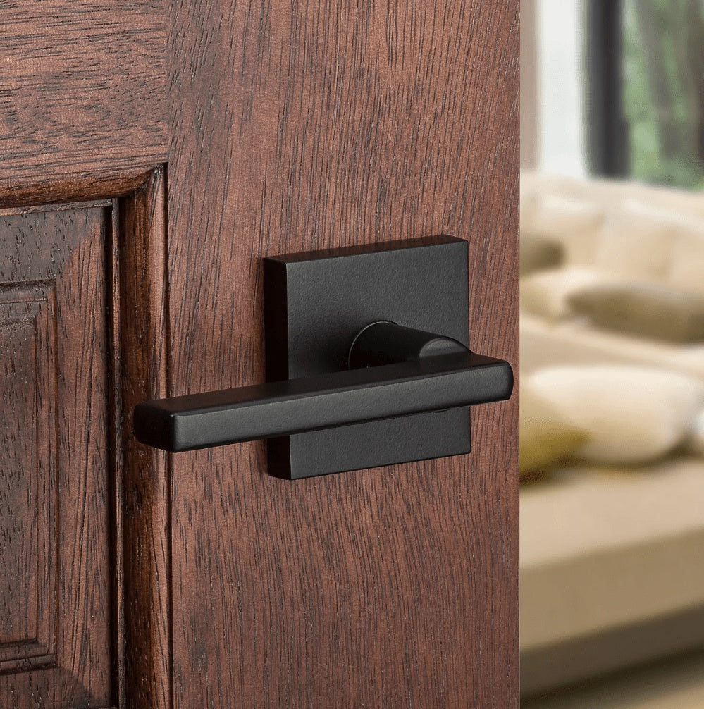 Kwikset Halifax square non-locking passage door lever in iron black finish mounted on a wooden door.