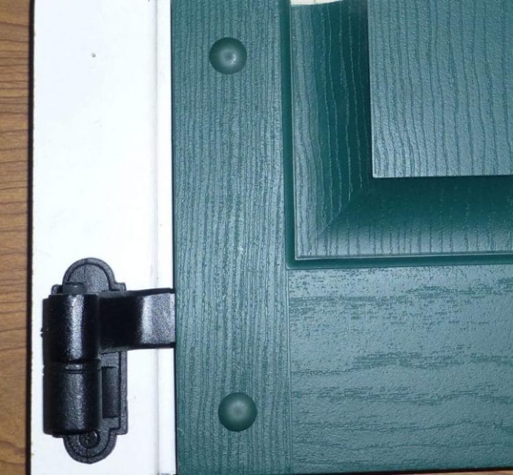 L Style shutter hinges in black powder coat, 4-1/2" x 3-1/2", cast iron, displayed on a green shutter. Sold in pairs.