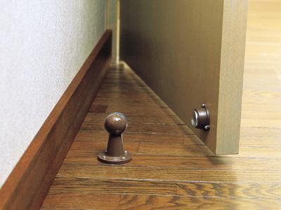 Magnetic door stop and holder mounted on the floor, holding a door open, available in multiple finishes.