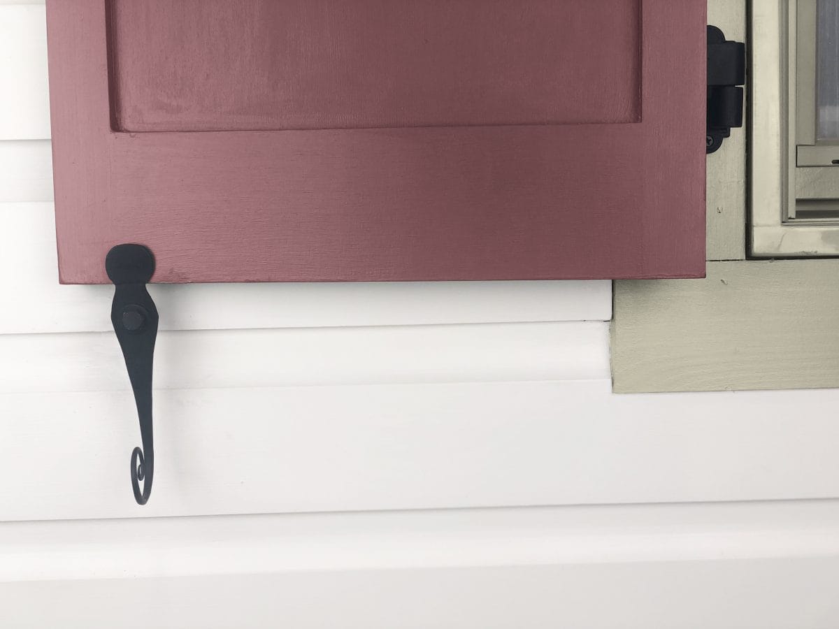 Black powder-coated forged steel shutter dogs, 6-inch English rat tail design, securely holding a shutter in place.