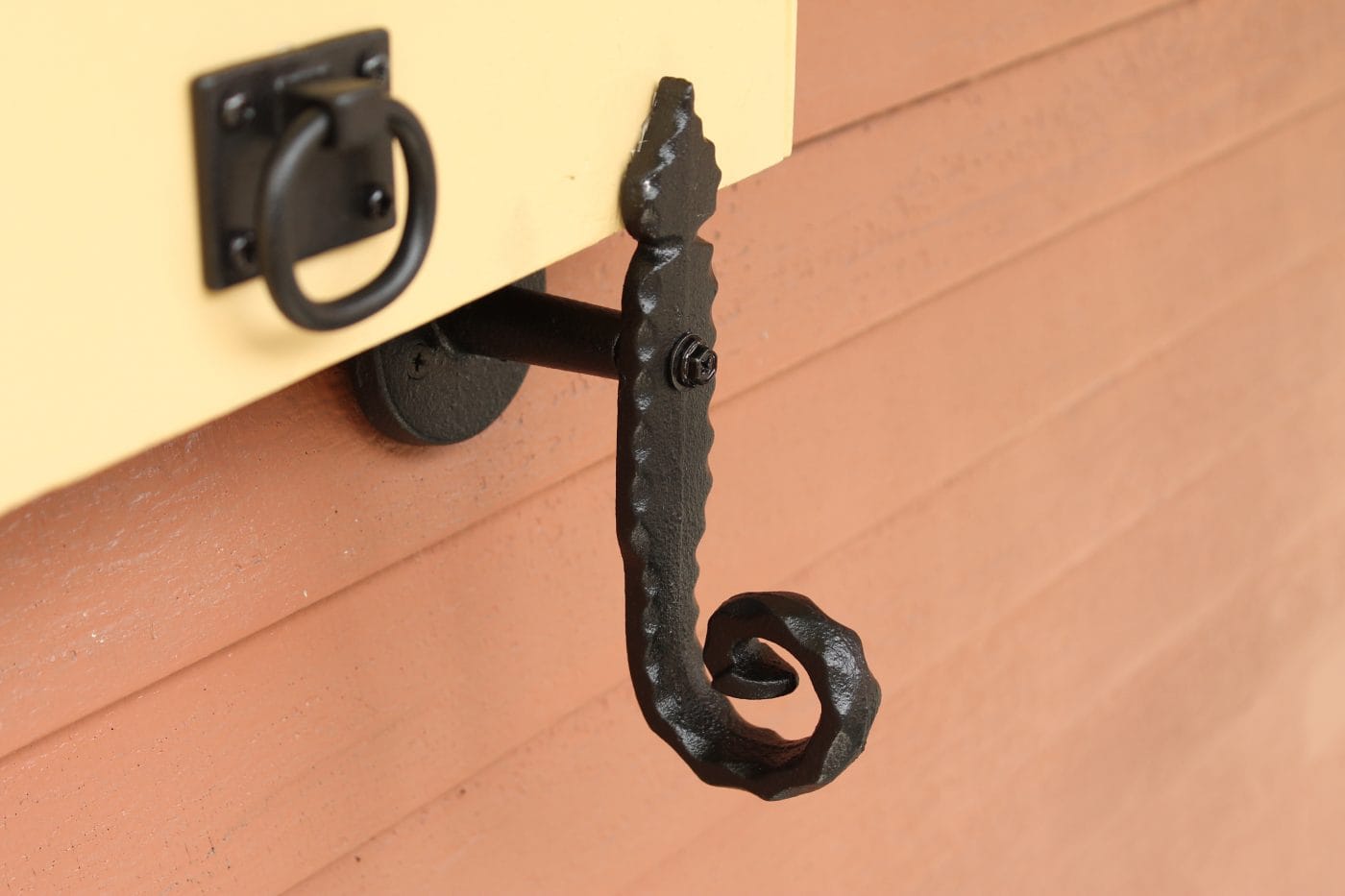 Black powder-coated cast iron shutter dog tieback in a rat tail design, 6-1/4 inches, sold in pairs.