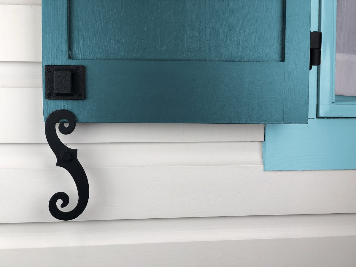 Stainless steel shutter dogs with a scroll design in black textured powder coat, ideal for securing shutters.
