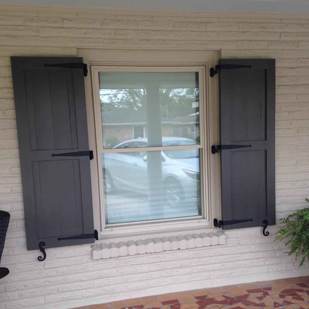 Black powder-coated strap hinge for shutters, 12 inches long with a 1-1/2 inch offset, displayed on a window.