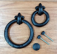 Fleur de Lis door knockers in two sizes, featuring a black finish and included mounting hardware.
