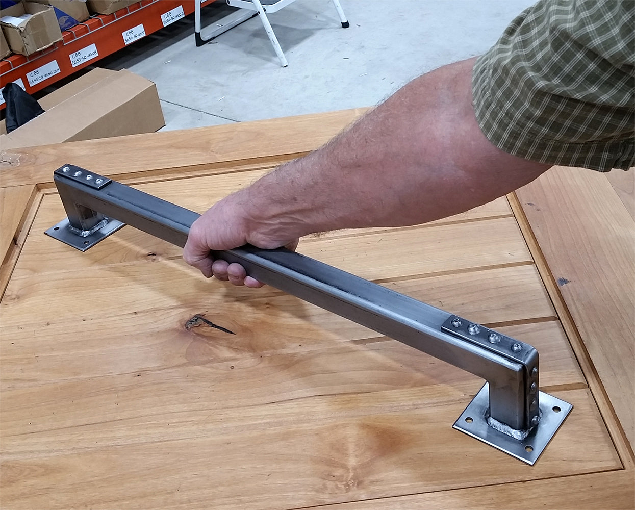 Industrial style barn door handle pull with studded bracket ends, 24 inches, shown being installed on wood.