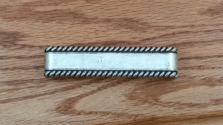Old silver drawer pull with a decorative rope edge design, sold individually for cabinets and furniture.