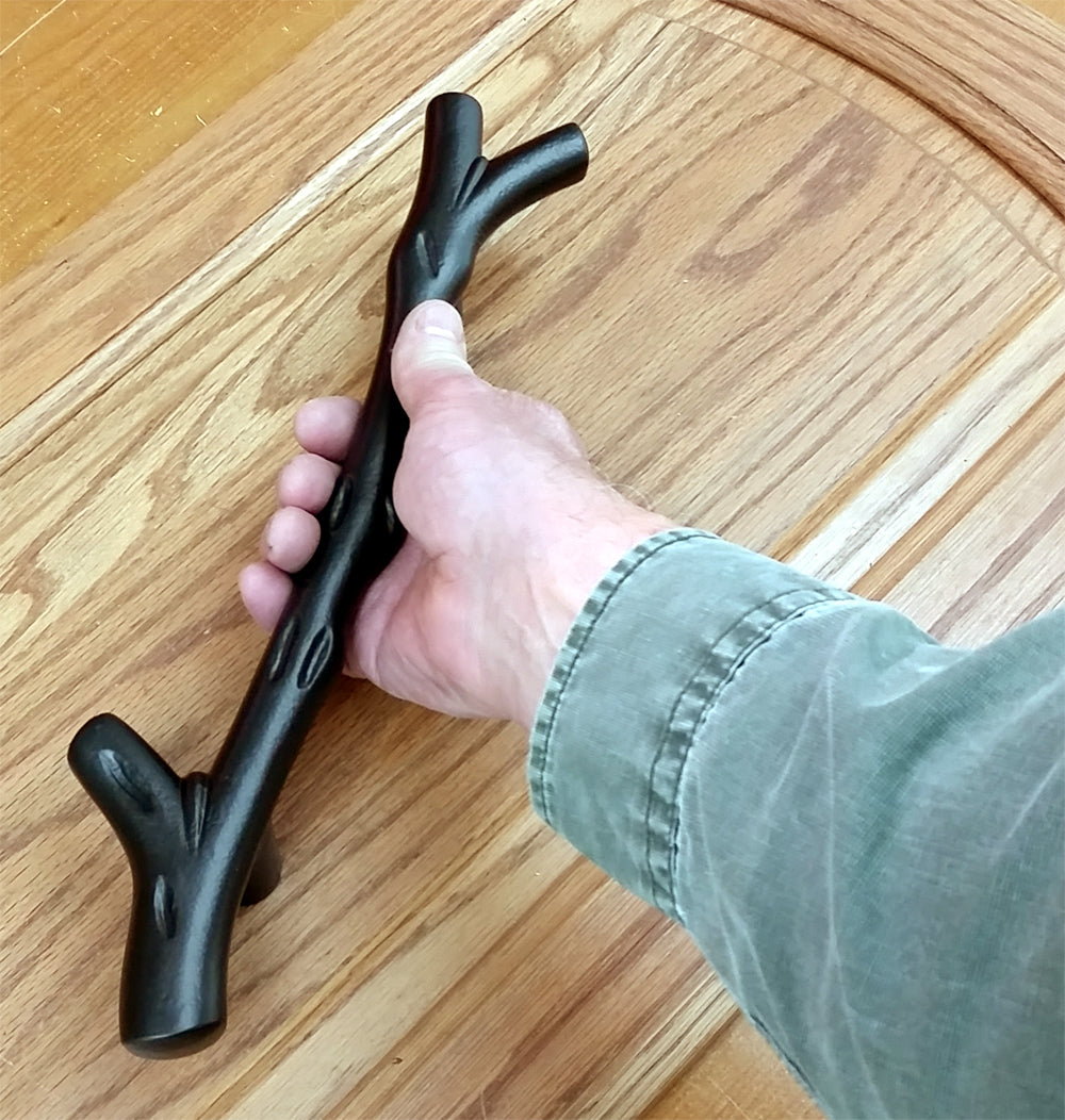 Tree branch handle pull for barn doors, 13-1/2 inches, shown in hand against wooden surface, available in multiple finishes.