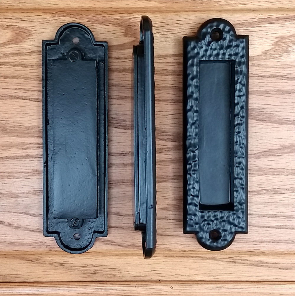 Flush pull barn door handles in black with a distressed, pitted finish, available in multiple sizes, sold individually.