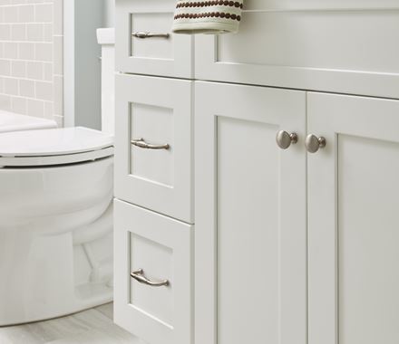 Edona Series cabinet knobs in various finishes, 1-1/4 inch, displayed on white cabinetry in a bathroom setting.