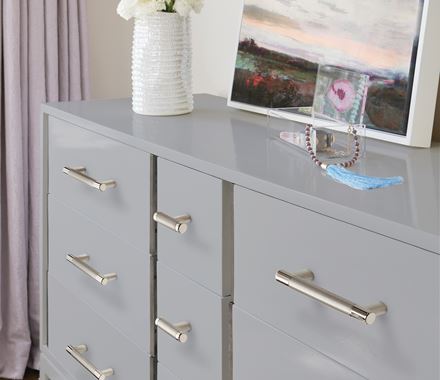 Polished nickel cabinet knobs from the Esquire Series on a modern dresser with drawers, enhancing contemporary decor.