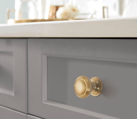 Revitalize Series cabinet knob in 1-1/4 inch size, shown in gold finish on a modern kitchen drawer.