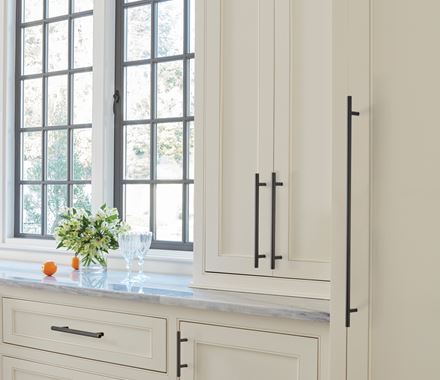 Sleek 3-inch bar pulls in various finishes enhance modern cabinetry in a bright kitchen setting.
