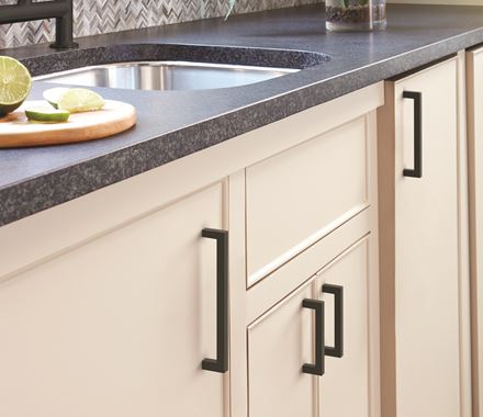 Matte black cabinet pulls from the Monument Series, 5-1/16" center to center, enhancing modern kitchen cabinetry.