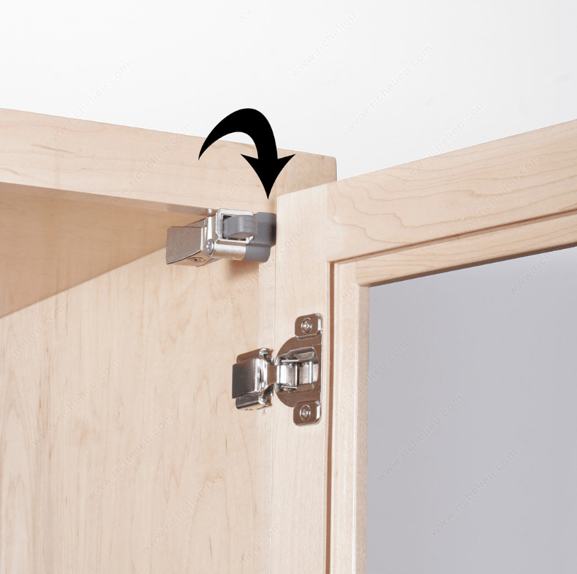 Cabinet hinge spacer designed for compact Blumotion hinges, shown installed on a wooden cabinet door.