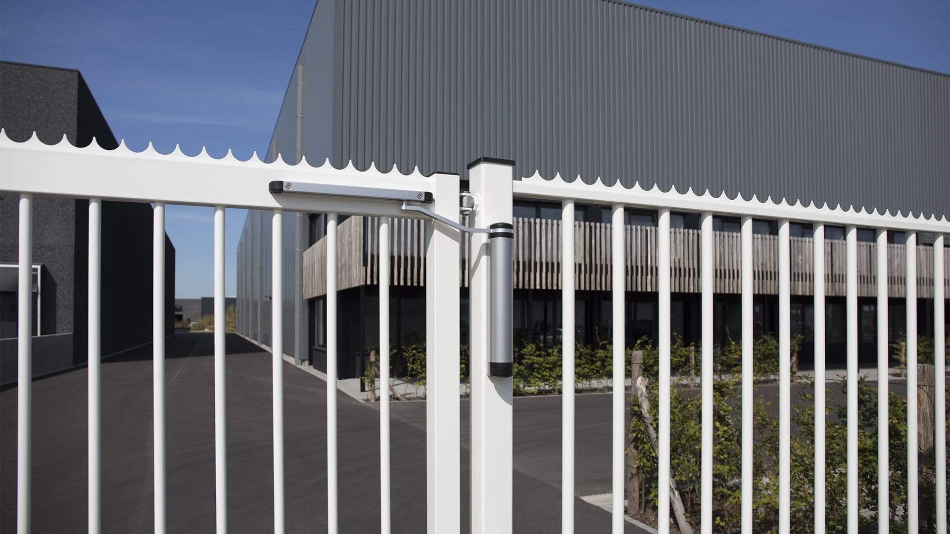 Hydraulic gate closer and lock kit installed on a white metal gate, suitable for residential retrofit applications.