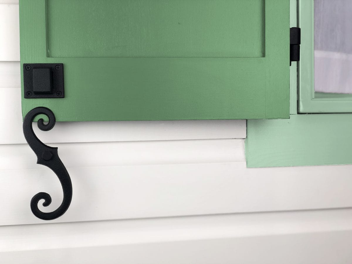 Beveled scroll shutter dogs in black powder coat, 6-3/4 inches, cast iron, sold in pairs for securing shutters.