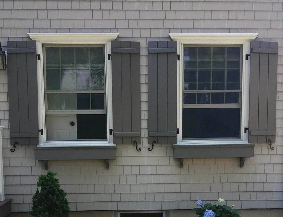 Black cast iron shutter dogs with a scroll design, 6-3/4 inches, securing window shutters in pairs.