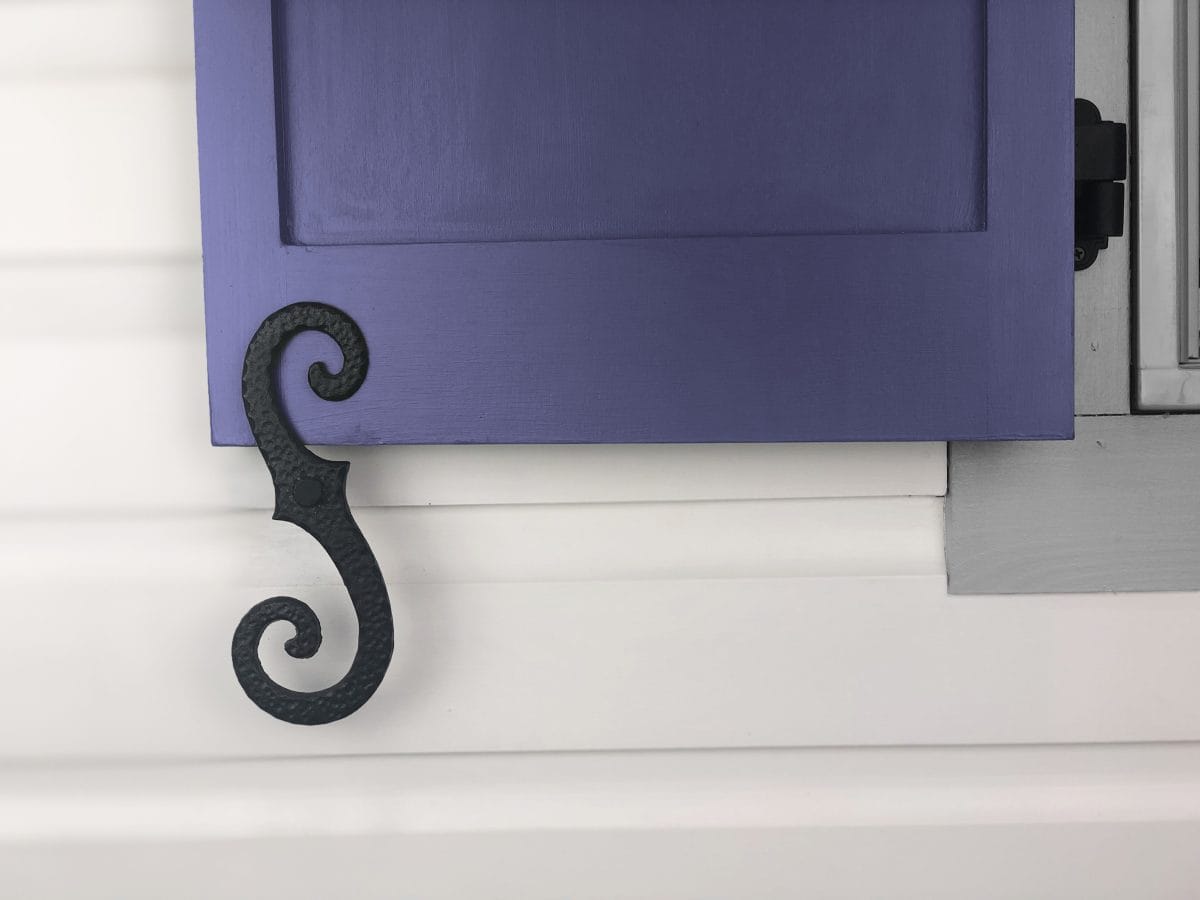 Stippled scroll shutter dogs in black powder coat, 8-inch cast iron, designed for securing shutters, sold in pairs.