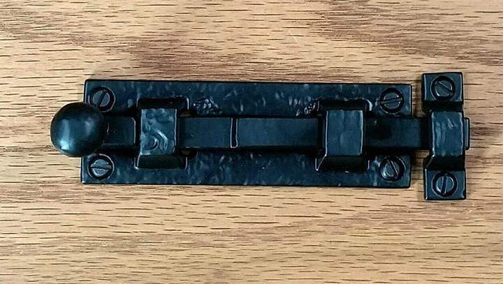 Small surface slide bolt for gates featuring a round ball handle and a durable black powder coat finish.
