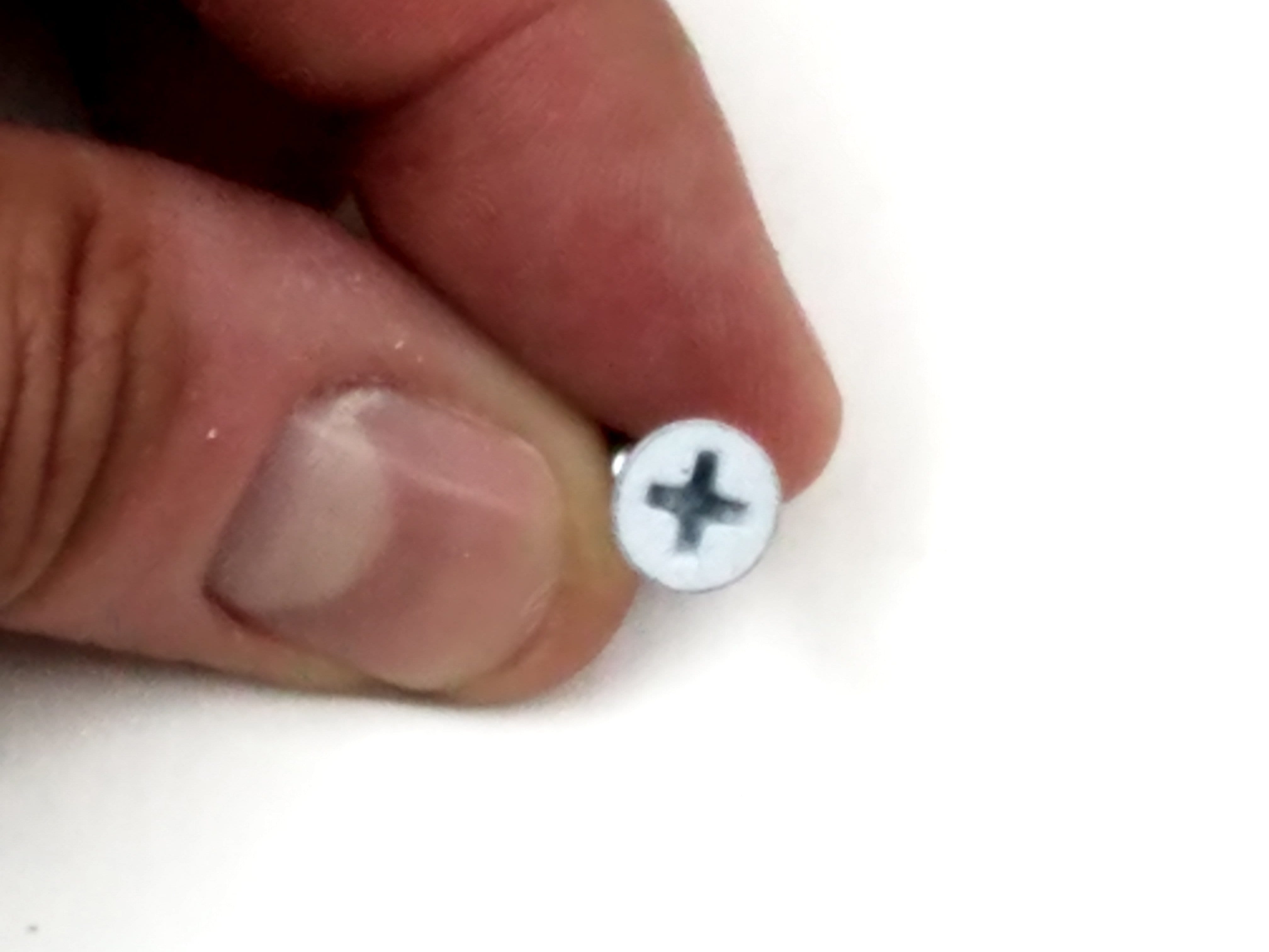 Fly cut wood screws for door hinges, white prime finish, #9 size, 3/4 inch length, held between fingers.